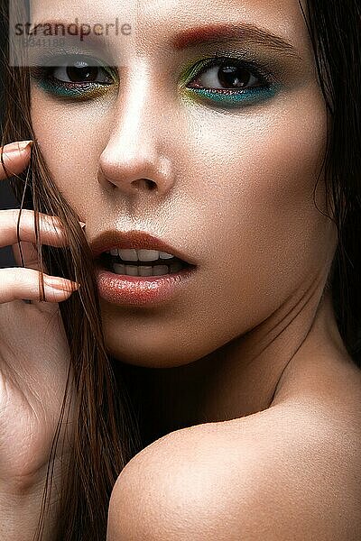 Schönes Mädchen mit einem hellen farbigen Make-up und nassen Haaren und Haut. Schönes Gesicht. Bild im Studio auf einem schwarzen Hintergrund genommen