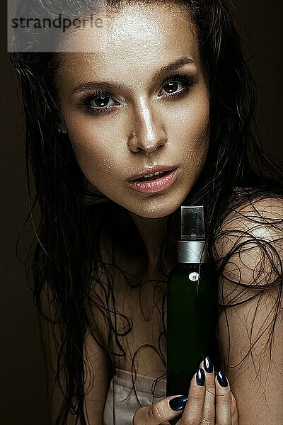 Schönes Mädchen mit einem hellen Make-up und nassen Haaren und Haut mit Flasche von kosmetischen Produkten in den Händen. Schönheit Gesicht. Bild im Studio auf einem schwarzen Hintergrund genommen