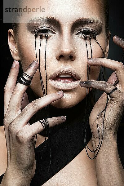 Schönes Mädchen mit kreativen Make-up im Gothic-Stil und die Fäden der Augen. Kunst Schönheit Gesicht. Bild im Studio auf einem schwarzen Hintergrund genommen