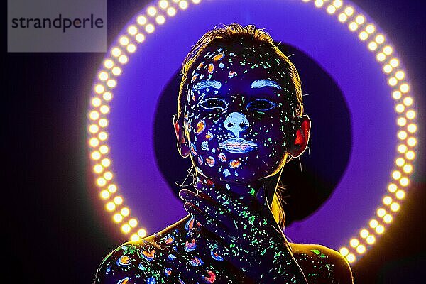 Porträt eines schönen Mädchens mit ultravioletter Farbe im Gesicht. Mädchen mit Neon-Make-up in Farbe Licht