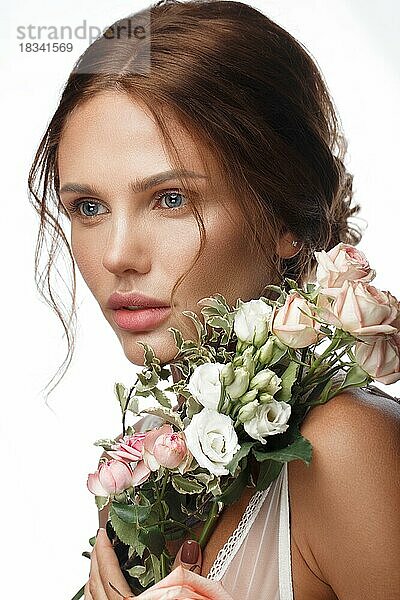 Schöne Frau mit klassischem Nackt-Make-up  heller Frisur und Blumen. Schönes Gesicht. Foto im Studio aufgenommen