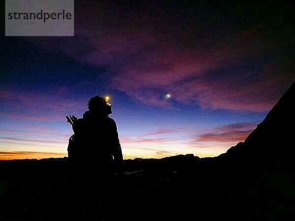 Silhouette einer Bergsteigerin mit Stirnlampe bei Morgendämmerung  Hoher Göll  Berchtesgadener Alpen  Nationalpark Berchtesgaden  Schönau am Königssee  Berchtesgadener Land  Oberbayern  Bayern  Deutschland  Europa