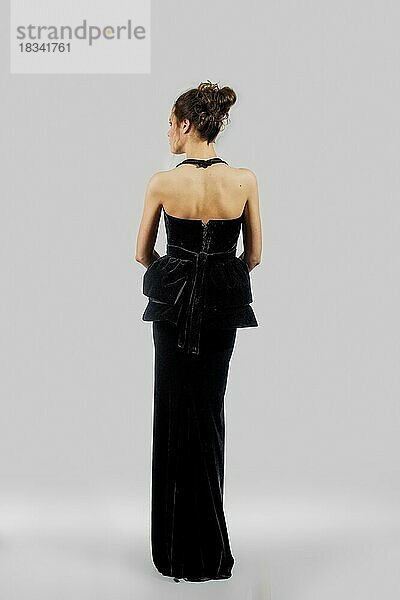 Schönes Modell demonstriert Abendkleid mit nackten Schultern. Porträt in voller Länge