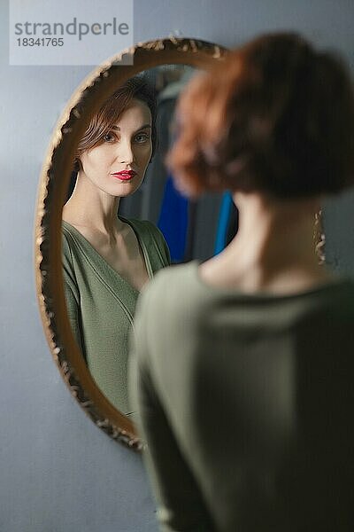 Porträt einer selbstbewussten  stilvollen Dame  die in den Wandspiegel schaut. Fokus auf Reflexion
