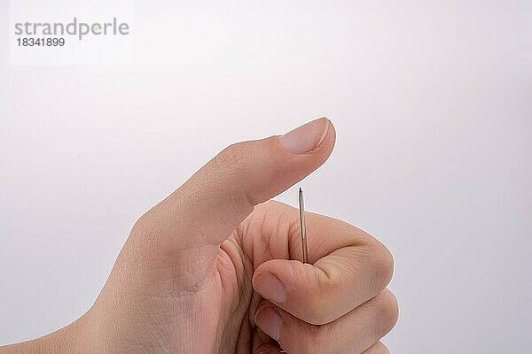 Hand hält eine Nadel auf weißem Hintergrund