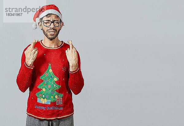 Mann mit Weihnachtsmütze wünscht sich etwas auf isoliertem Hintergrund  Hoffnungsvoller Mann in Weihnachtskleidung wünscht sich etwas  Schöner Mann mit Weihnachtsmütze wünscht sich etwas auf weißem Hintergrund