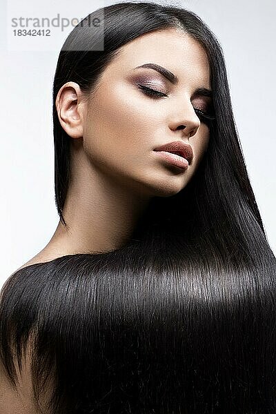 Schönes brünettes Mädchen in Bewegung mit einem perfekt glatten Haar  und klassisches Make-up. Schönheit Gesicht. Bild im Studio auf einem weißen Hintergrund genommen