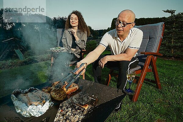 Pärchen beim Grillen am späten Abend. Glückliches Paar beim Grillen im Hinterhof