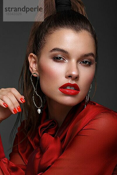 Schönes frisches Mädchen mit klassischem Make-up  glatten Haaren in einem roten Kleid. Schönes Gesicht. Foto im Studio aufgenommen