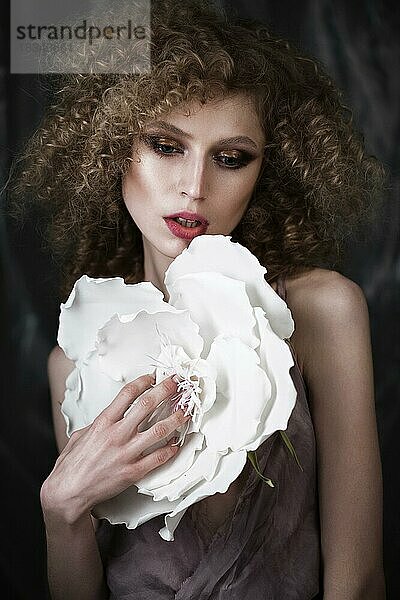 Schönes Mädchen mit lockigem Haar in Dessous mit großer Blume. Die Schönheit des Gesichts. Fotos im Studio geschossen