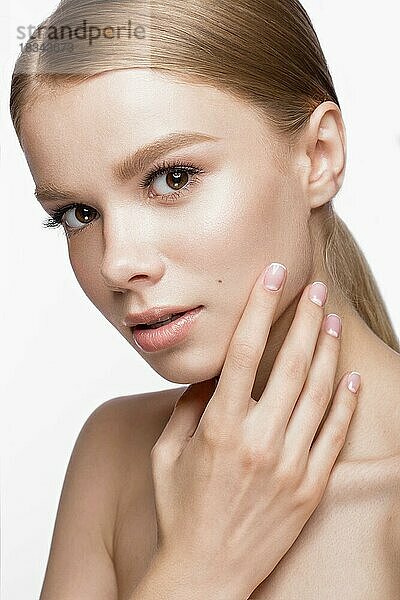 Schönes junges Mädchen mit einem leichten natürlichen Make-up und französischer Maniküre. Schönes Gesicht. Bild im Studio auf einem weißen Hintergrund aufgenommen