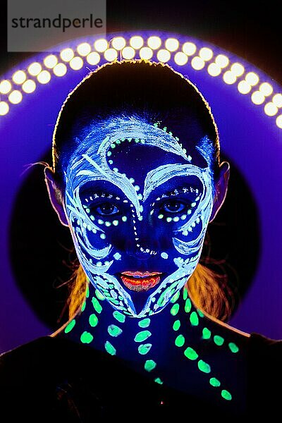 Porträt eines schönen Mädchens mit ultravioletter Farbe im Gesicht. Mädchen mit Neon-Make-up in Farbe Licht