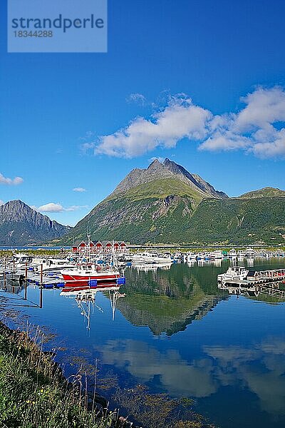 Holzhäuser  kleine Fischerboote und steile Berge spiegeln sich im Wasser eines Hafens  Aldersund  FV 17  Kystriksveien  Nordland  Norwegen  Europa