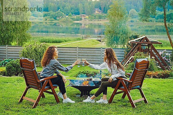 Zwei Frauen stoßen im Hinterhof mit Weingläsern an