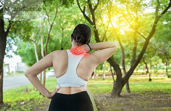 Laufende Frau mit Schultermuskelschmerzen in einem Park. Schulterschmerzen Konzept eines Läufers Athleten. Athleten Mädchen in Schmerzen reiben ihre Schulter im Freien. Rückenansicht einer sportlichen Frau mit Schulterschmerzen