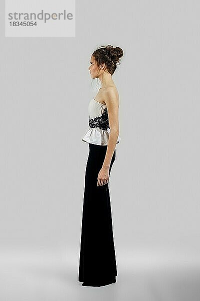 Schönes Modell demonstriert Abendkleid mit nackten Schultern. Porträt in voller Länge