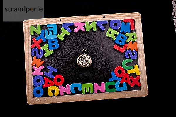 Taschenuhr und bunte Buchstaben des Alphabets aus Holz