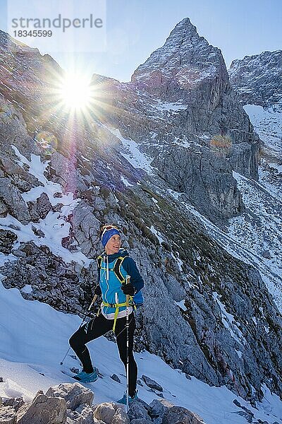 Bergsteigerin im verschneiten  felsigen Gelände genießt die Aussicht  hinten die Blaueisspitze  Hochkalter  Nationalpark Berchtesgaden  Ramsau  Berchtesgadener Land  Oberbayern  Bayern  Deutschland  Europa