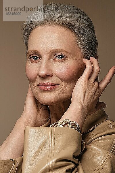 Porträt einer schönen älteren Frau in einem beigen Regenmantel mit klassischem Make-up und grauem Haar