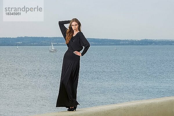 Attraktive Mode-Modell in langen schwarzen Kleid posiert auf dem Pier
