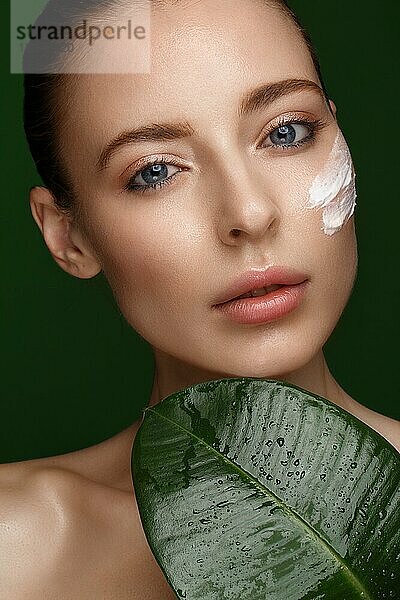 Schönes frisches Mädchen mit perfekter Haut  natürlichem Make-up und grünen Blättern. Schönes Gesicht. Foto im Studio aufgenommen