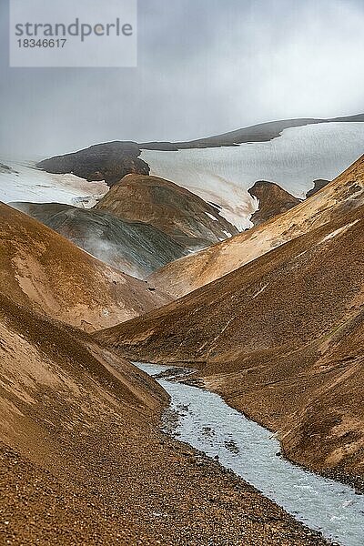 Dampfender Bach zwischen bunten Rhyolith Bergen und Schneefeldern  Geothermalgebiet Hveradalir  Kerlingarfjöll  isländisches Hochland  Island  Europa