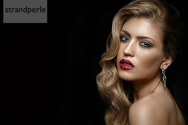 Schönes Mädchen mit roten Lippen und klassischem Make-up und Locken. Schönes Gesicht. Foto im Studio aufgenommen