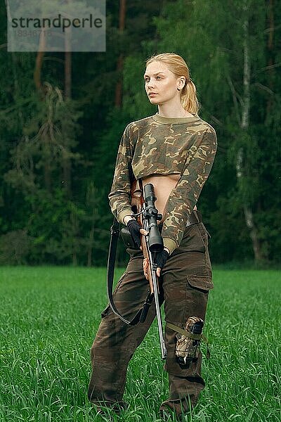 Attraktives Jägermädchen mit Jagdkarabiner  das auf die Trophäe im äußeren Wald schaut