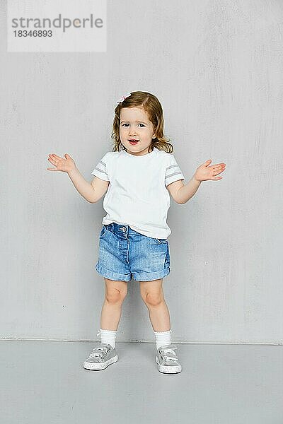 Zwei Jahre altes Mädchen in weißem t-short und Jeans-Shorts posiert im Studio