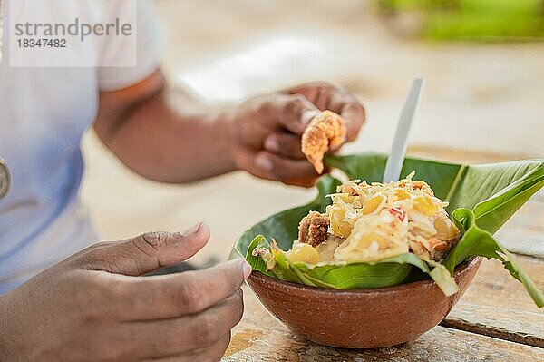 Nahaufnahme einer Person  die einen Vigorón am Tisch isst. Einheimischer  der einen traditionellen Vigorón isst. Der vigoron typisches Essen von Granada  Konzept der typischen Lebensmittel von Nicaragua