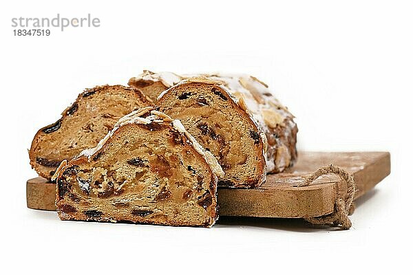 Deutscher Stollen  ein Früchtebrot mit Nüssen  Gewürzen und getrockneten oder kandierten Früchten mit Puderzucker  das traditionell zur Weihnachtszeit auf einem Schneidebrett serviert wird  vor weißem Hintergrund