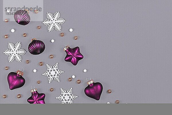 Weihnachten flach legen mit lila Herz und Stern geformt und Runde Baumschmuck Kugeln und weiße Schneeflocken auf grauem Hintergrund mit leeren Kopie Raum auf Seite