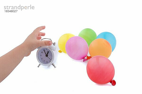 Hand hält einen Wecker mit Luftballons auf dem weißen Hintergrund