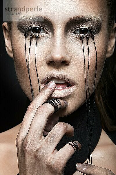Schönes Mädchen mit kreativen Make-up im Gothic-Stil und die Fäden der Augen. Kunst Schönheit Gesicht. Bild im Studio auf einem schwarzen Hintergrund genommen