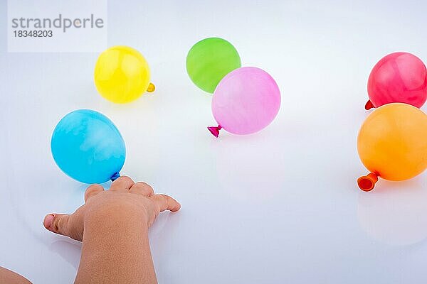 Hand hält bunte Luftballons auf einem weißen Hintergrund