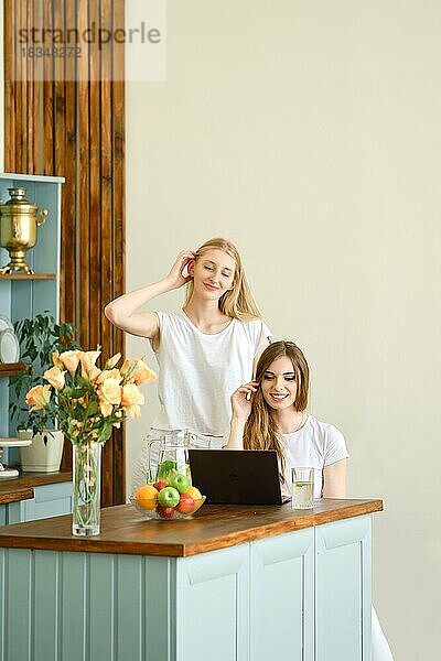 Zwei schöne Studentinnen machen eine Videokonferenz in der Küche