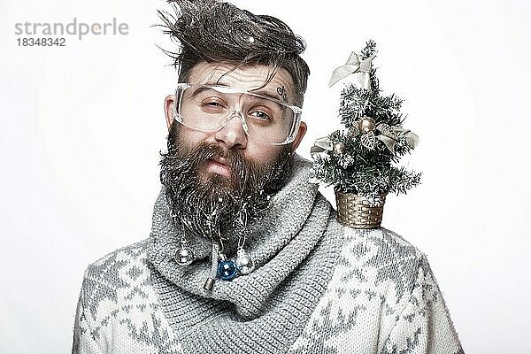 Lustiger bärtiger Mann in einem Neujahrsbild mit Schnee und Dekorationen auf seinem Bart. Fest der Weihnacht. Fotos im Studio aufgenommen