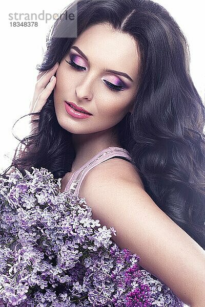 Schönes brünettes Mädchen mit einem sanften romantischen Make-up  rosa Lippen und Blumen. Die Schönheit des Gesichts. Porträtaufnahme im Studio