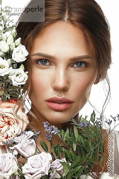 Schöne Frau mit klassischem Nackt-Make-up  heller Frisur und Blumen. Schönes Gesicht. Foto im Studio aufgenommen