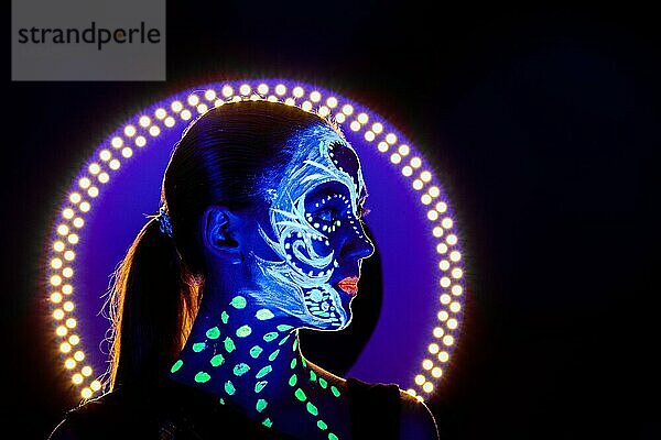 Porträt eines schönen Mädchens mit ultravioletter Farbe im Gesicht. Mädchen mit Neon-Make-up in Farbe Licht