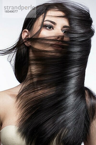 Schönes brünettes Mädchen in Bewegung mit einem perfekt glatten Haar  und klassisches Make-up. Schönheit Gesicht. Bild im Studio auf einem weißen Hintergrund genommen