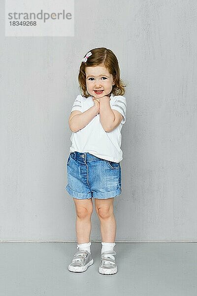 Zwei Jahre altes Mädchen in weißem t-short und Jeans-Shorts posiert im Studio