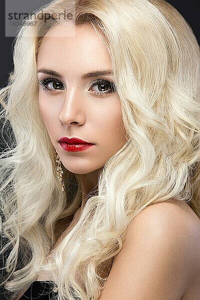 Schöne blonde Frau mit Abend-Make-up  roten Lippen und Locken. Schönes Gesicht. Bild im Studio auf einem grauen Hintergrund genommen