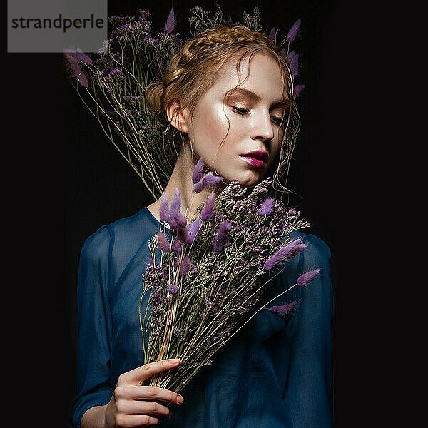 Schönes Mädchen mit einem sanften Make-up und Frisur in Form von Zöpfen  trockene Blumen in ihren Händen. Schönes Gesicht. Bild im Studio aufgenommen