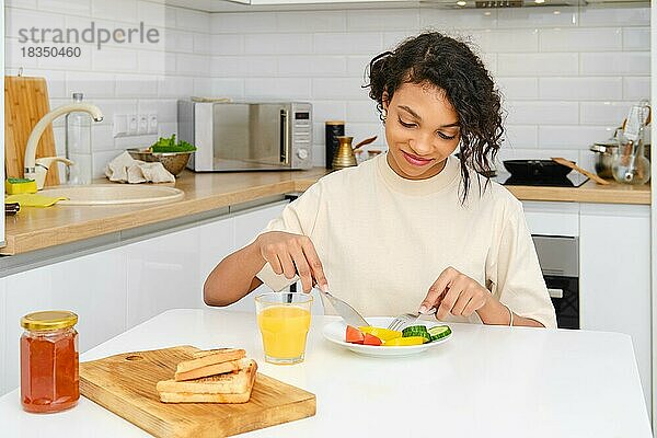 Junge afroamerikanische Frau beim traditionellen Frühstück zu Hause