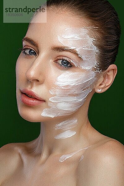 Schönes frisches Mädchen mit kosmetischer Creme auf dem Gesicht  natürliches Make-up. Schönes Gesicht. Foto im Studio aufgenommen