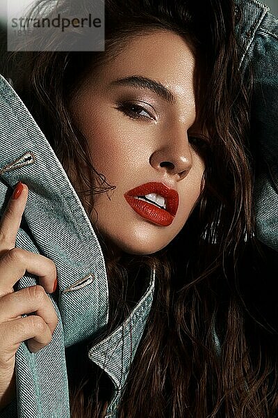 Schöne sexy Mädchen mit hellen Make-up  rote Lippen  nasse Haare in einer Jeansjacke. Schönes Gesicht. Foto im Studio aufgenommen