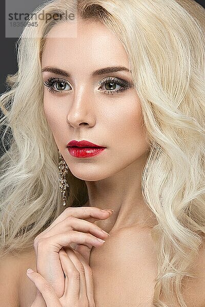 Schöne blonde Frau mit Abend-Make-up  roten Lippen und Locken. Schönes Gesicht. Bild im Studio auf einem grauen Hintergrund genommen