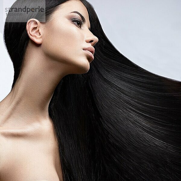 Schönes brünettes Mädchen in Bewegung mit einem perfekt glatten Haar  und klassisches Make-up. Schönheit Gesicht. Bild im Studio auf einem weißen Hintergrund genommen