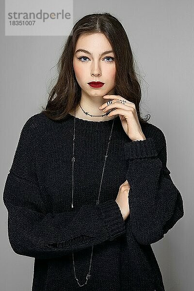 Wunderschöne Model-Dame mit natürlichem Make-up und brünetten Haaren. Studio-Modeaufnahme auf grauem Hintergrund  perfekte Haut  matte rote Lippen